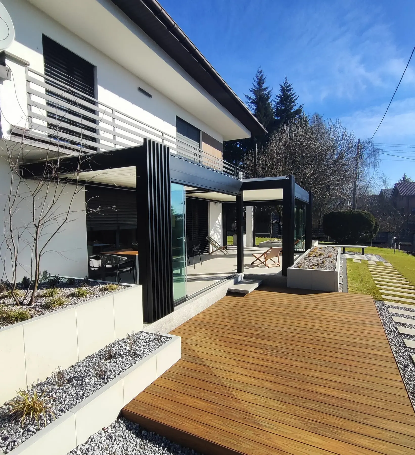 Anthrazitfarbene Aluminium-Pergola als Teil der Terrassenanlage eines modernen Wohnhauses